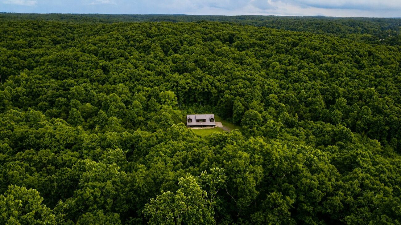 Aerial of the barndominium tucked into its clearing in the trees